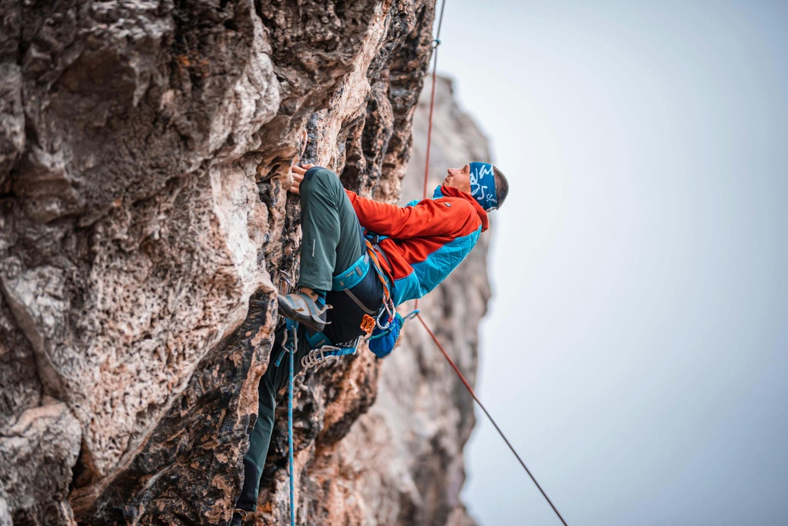 A climber scaling a rugged, rocky cliff face, showcasing the skill and physical strength required for outdoor rock climbing.